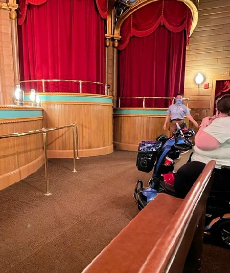 Image of a mobility scooter, in place, at Grizzly Hall.  The scooter is facing the stage of the Country Bear Jamboree.